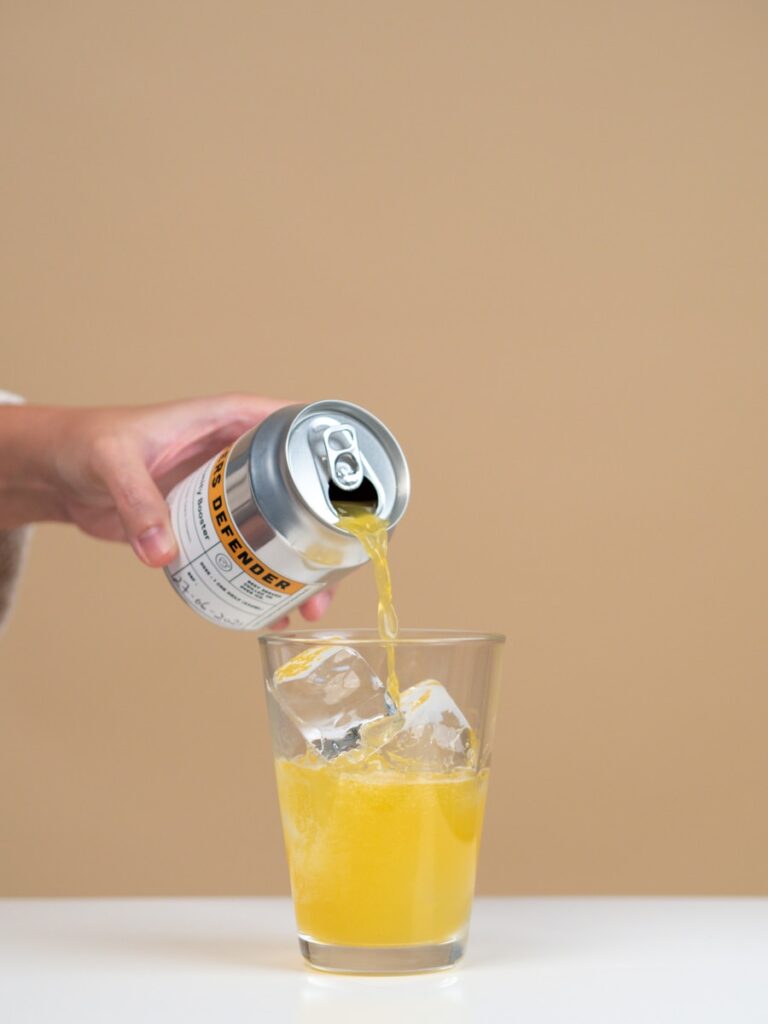 person holding white and black can