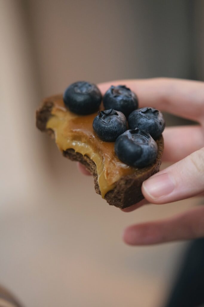 a person holding a piece of food with blueberries on it