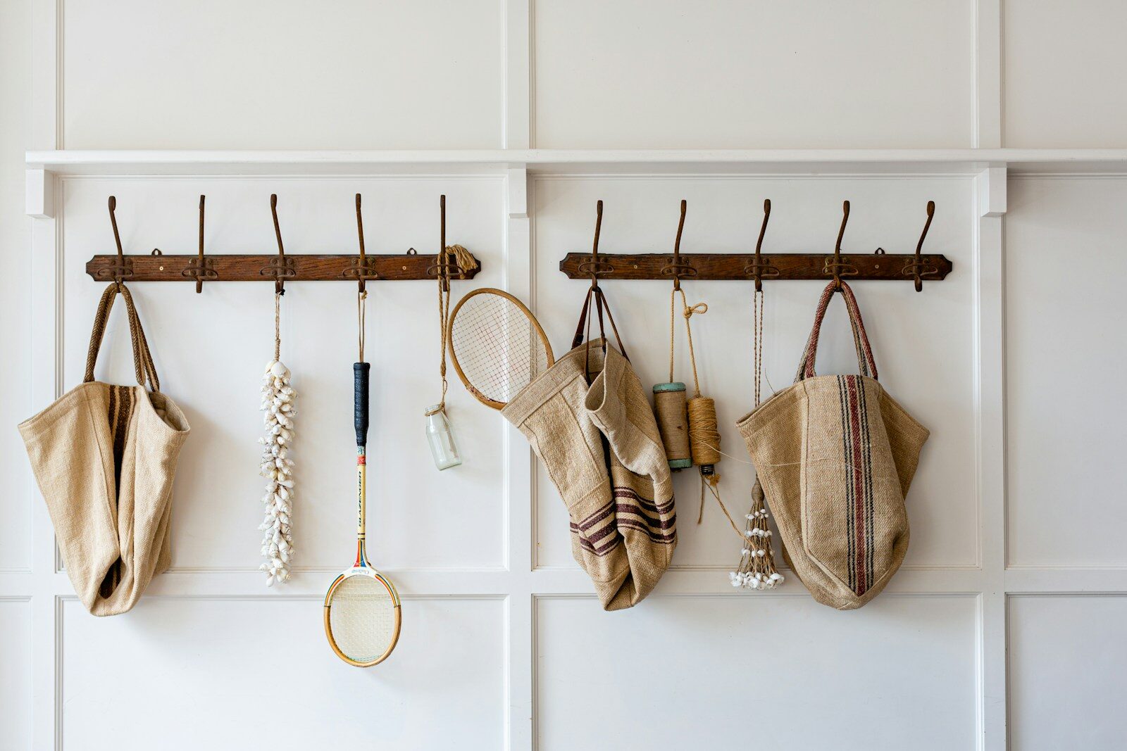 Photo by Luisa Brimble brown and white sling bags hanged on white wooden wall