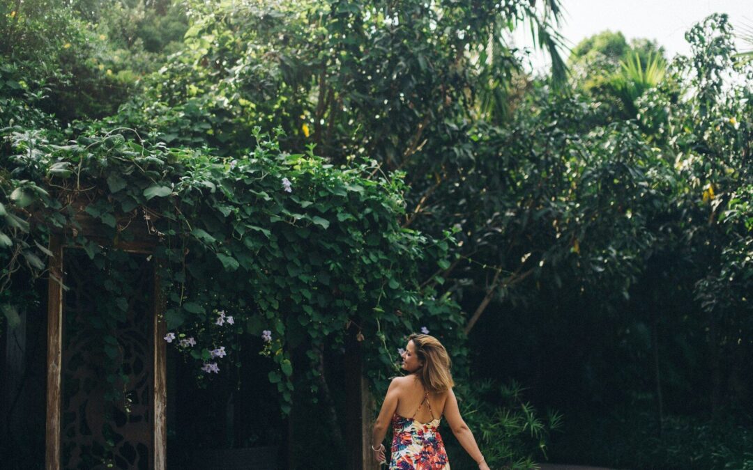 woman in blue and red floral dress standing near green trees during daytime