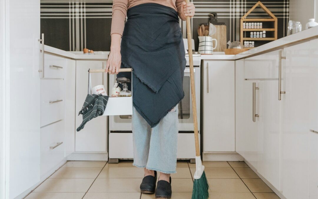 a woman standing in a kitchen holding a broom