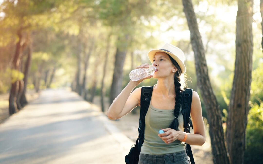a woman in a hat drinking water from a bottle