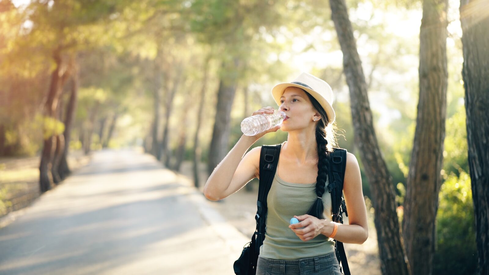 a woman in a hat drinking water from a bottle