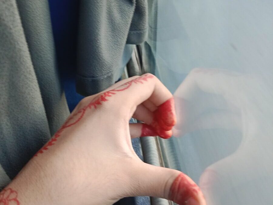 A person's hand with a red tattoo on their left hand